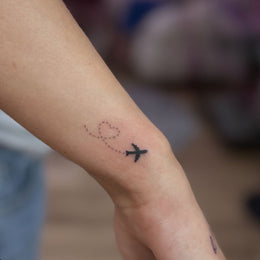 Kleines Flugzeug-Motiv am Knöchel – Tattoo aus Köln