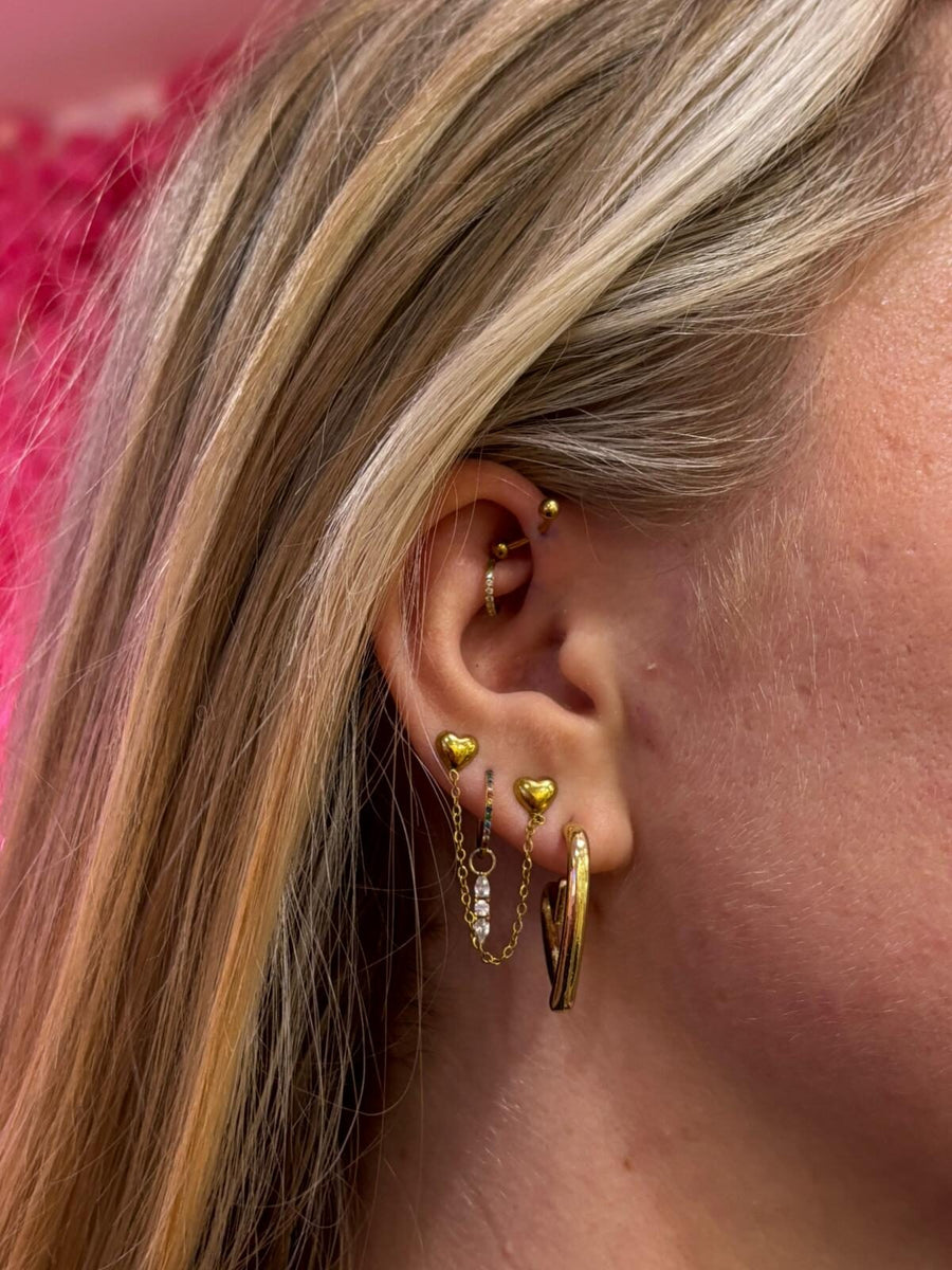 Mehrere Ohrpiercings mit Goldschmuck: Helix, zwei Lobes mit Herzsteckern und Kettchen